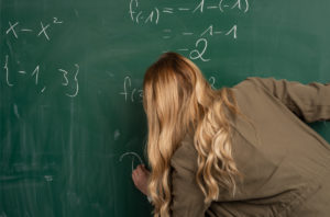 Schülerin erklärt eine mathematische Aufgabe an der Tafel im Unterricht.